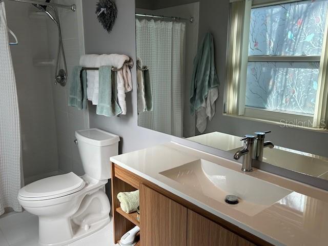 bathroom featuring vanity, curtained shower, and toilet