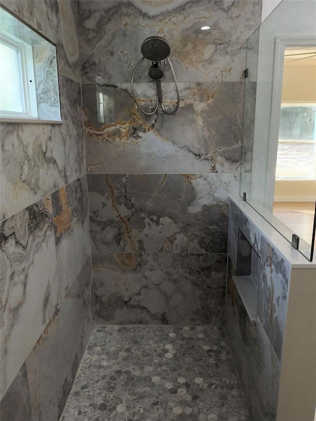 bathroom featuring plenty of natural light and tiled shower