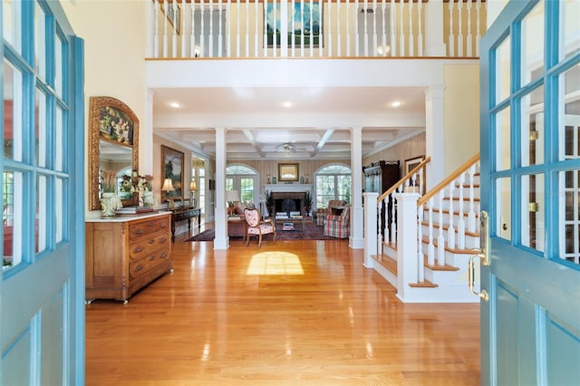 entrance foyer with ornate columns, coffered ceiling, and light hardwood / wood-style floors