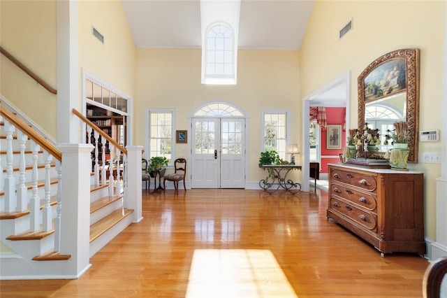 entryway with high vaulted ceiling, a healthy amount of sunlight, and light wood-type flooring