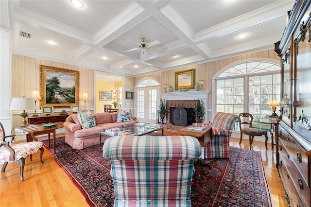 living room with french doors, coffered ceiling, beamed ceiling, a brick fireplace, and hardwood / wood-style flooring