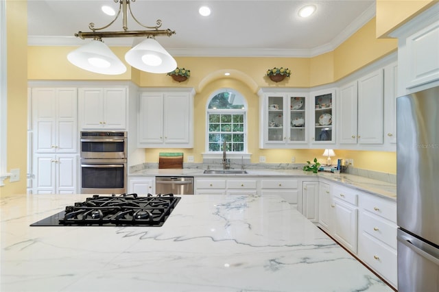 kitchen featuring pendant lighting, sink, stainless steel appliances, light stone counters, and white cabinets