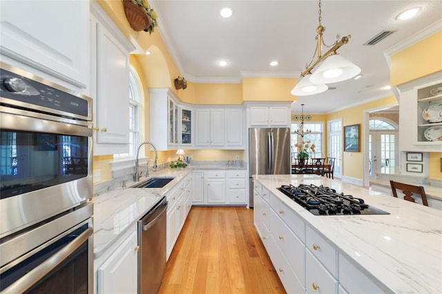 kitchen with pendant lighting, stainless steel appliances, sink, and white cabinets