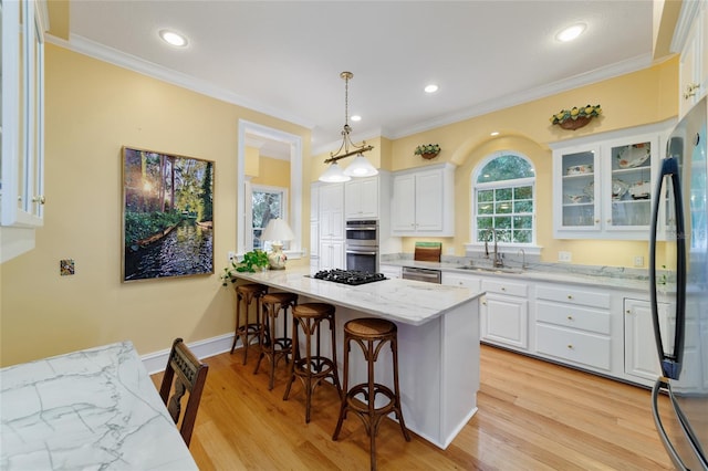 kitchen with white cabinetry, hanging light fixtures, a breakfast bar area, and sink