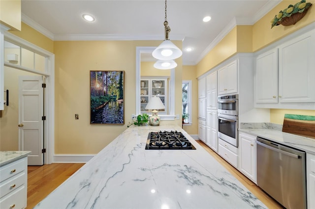 kitchen featuring appliances with stainless steel finishes, pendant lighting, white cabinetry, crown molding, and light stone countertops