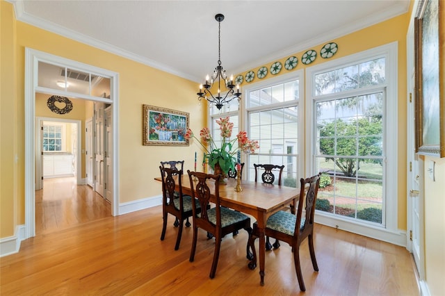 dining space with crown molding, a notable chandelier, and light wood-type flooring