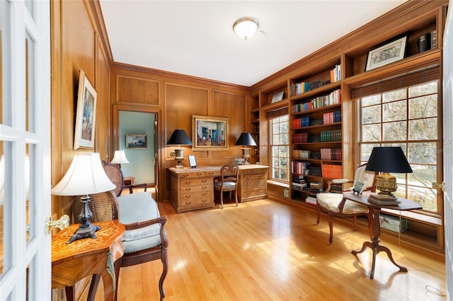 office featuring light hardwood / wood-style flooring, ornamental molding, wooden walls, and a healthy amount of sunlight