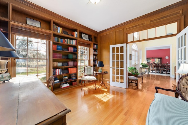 office featuring ornamental molding, light hardwood / wood-style floors, french doors, and wooden walls