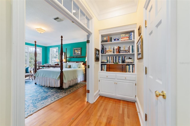 bedroom with ornamental molding and light hardwood / wood-style floors