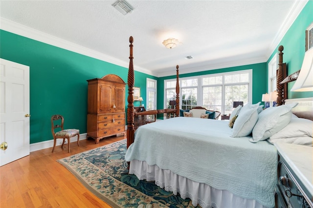 bedroom featuring ornamental molding, a textured ceiling, and light hardwood / wood-style flooring