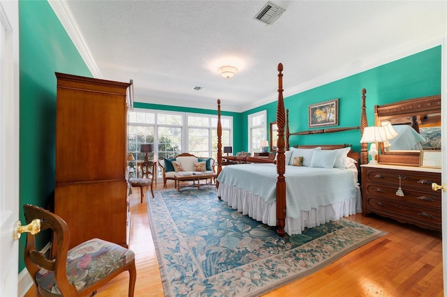 bedroom featuring ornamental molding, a textured ceiling, and light hardwood / wood-style floors