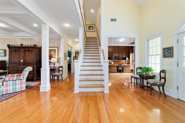 foyer with decorative columns, a towering ceiling, beamed ceiling, and light hardwood / wood-style flooring