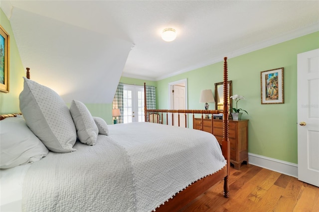 bedroom with wood-type flooring, crown molding, and french doors