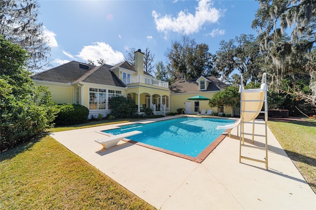 view of pool featuring a yard, a patio area, a diving board, and a water slide