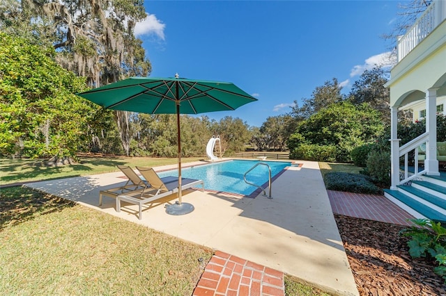 view of pool with a water slide, a patio, and a lawn