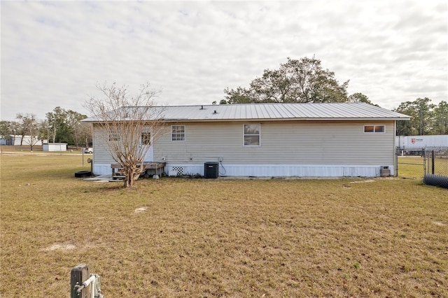 rear view of house with cooling unit and a yard