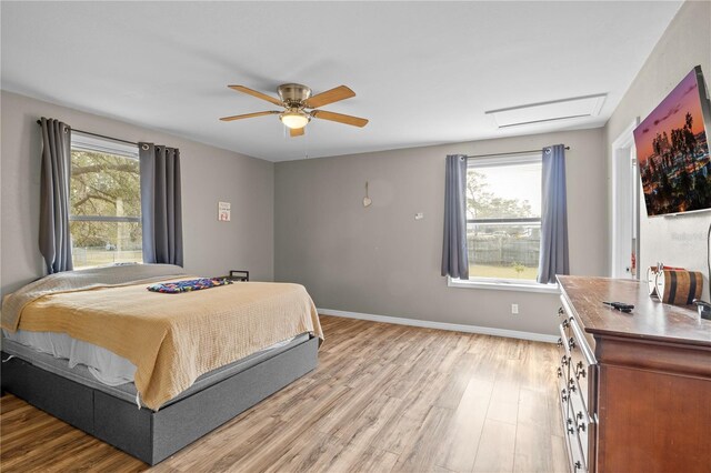 bedroom featuring ceiling fan, light hardwood / wood-style floors, and multiple windows