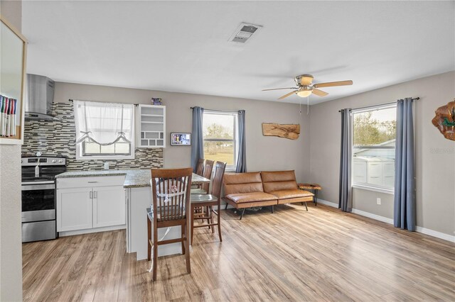 kitchen featuring white cabinetry, a healthy amount of sunlight, stainless steel electric range oven, and light wood-type flooring