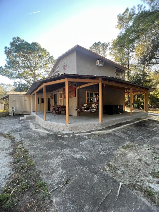 view of home's exterior with a wall mounted AC and a patio