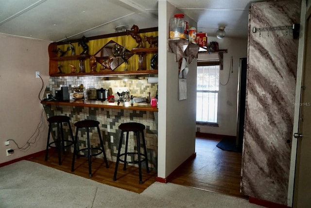 bar featuring tasteful backsplash, vaulted ceiling, and dark wood-type flooring