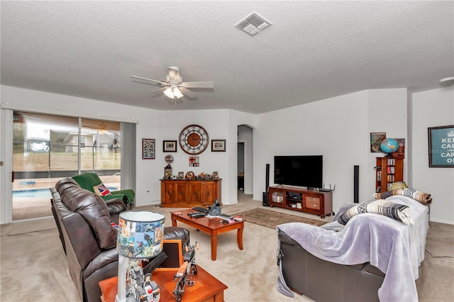 carpeted living room featuring ceiling fan and a textured ceiling