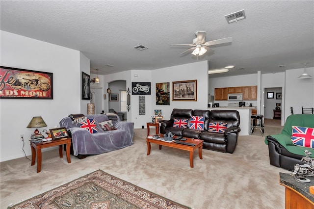 living room with light carpet, ceiling fan, and a textured ceiling