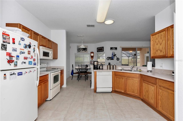 kitchen featuring sink, hanging light fixtures, white appliances, kitchen peninsula, and a textured ceiling