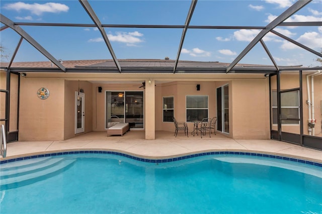 view of pool with a patio, ceiling fan, and glass enclosure