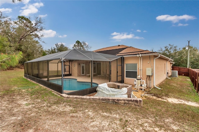 rear view of property with a patio, a lawn, cooling unit, a lanai, and a fenced in pool