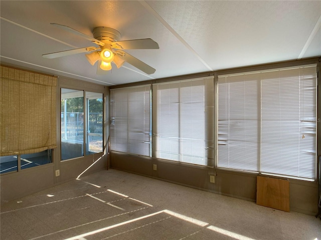 unfurnished sunroom featuring ceiling fan and a healthy amount of sunlight