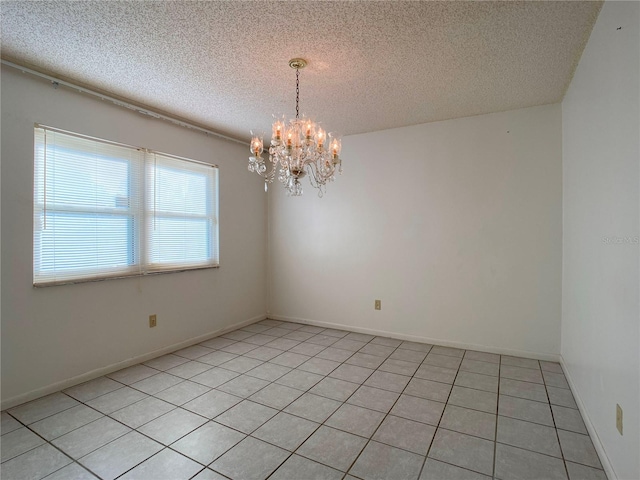 spare room featuring an inviting chandelier and a textured ceiling