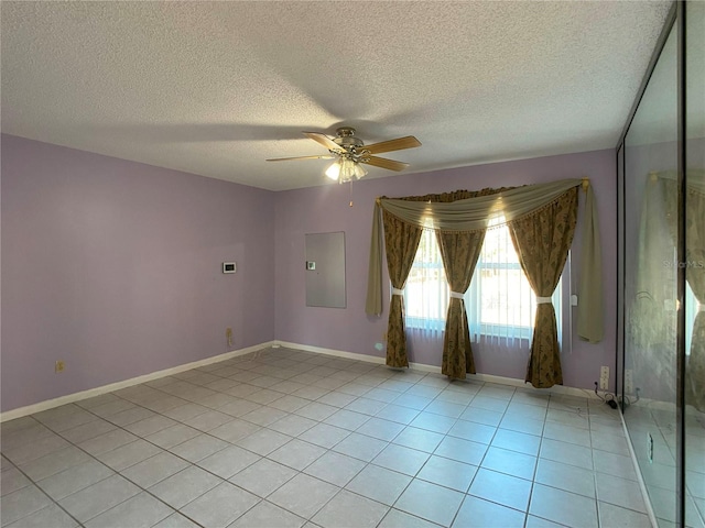 spare room with light tile patterned flooring, a textured ceiling, electric panel, and ceiling fan