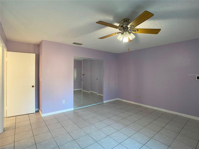 unfurnished bedroom with ceiling fan, a textured ceiling, a closet, and light tile patterned floors