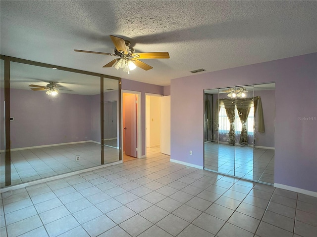 unfurnished bedroom with light tile patterned floors, a textured ceiling, and ceiling fan