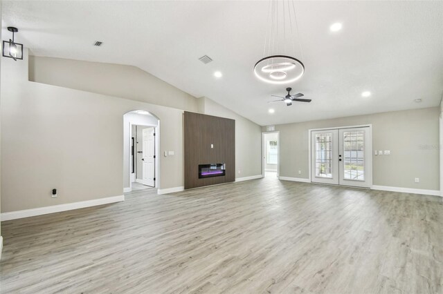 unfurnished living room with french doors, visible vents, vaulted ceiling, and light wood finished floors