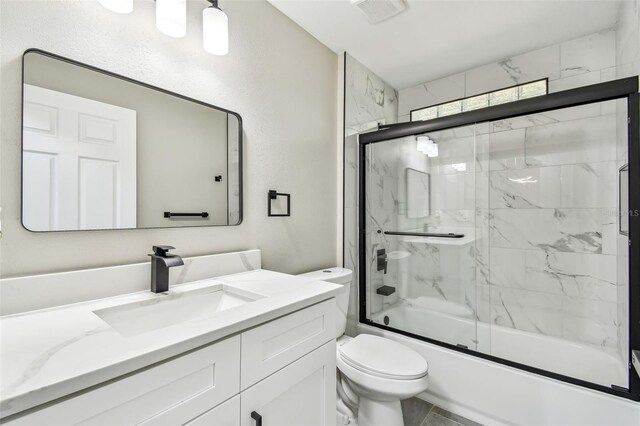 full bathroom featuring visible vents, vanity, toilet, and bath / shower combo with glass door