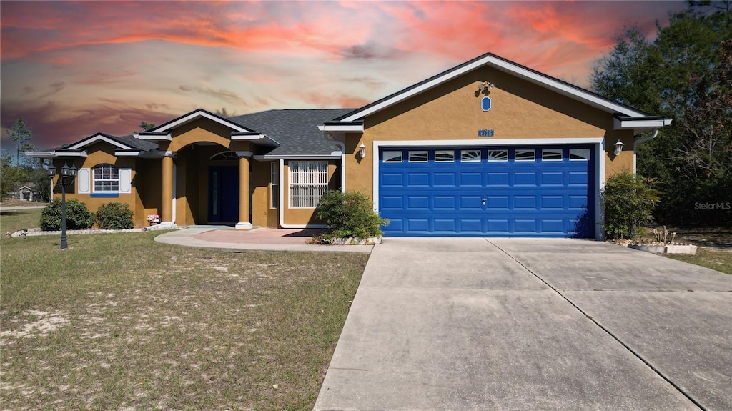 ranch-style home featuring a garage and a yard