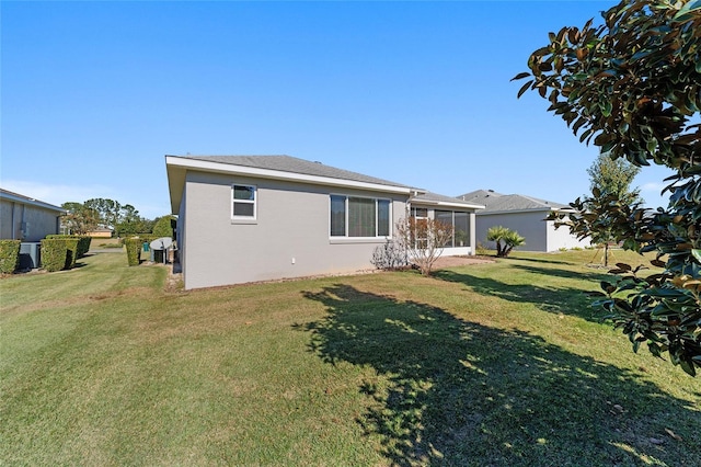 back of property with a lawn and a sunroom