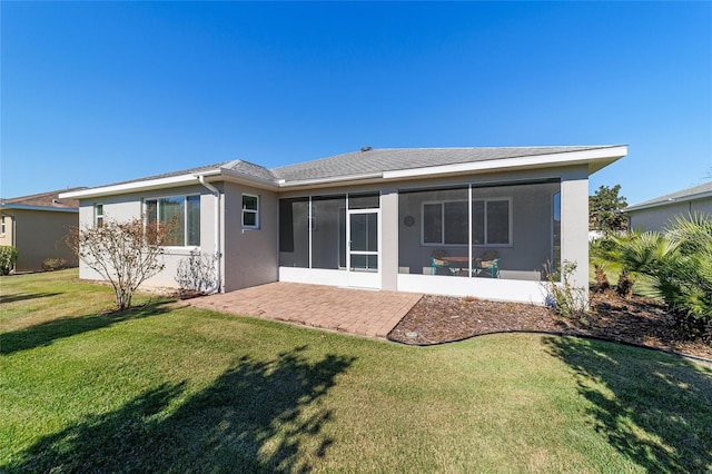 rear view of property featuring a lawn, a sunroom, and a patio area