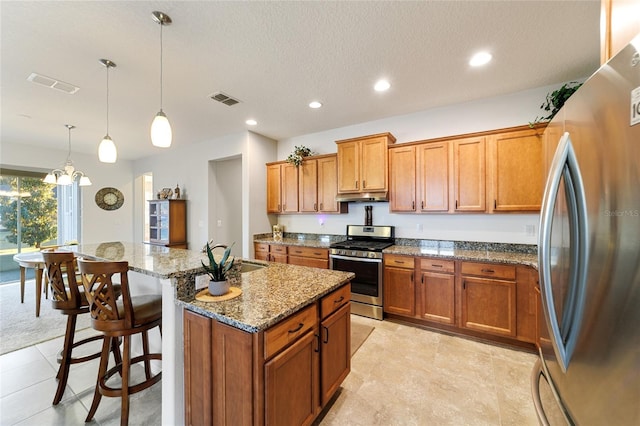 kitchen featuring stone countertops, pendant lighting, an island with sink, a kitchen breakfast bar, and stainless steel appliances