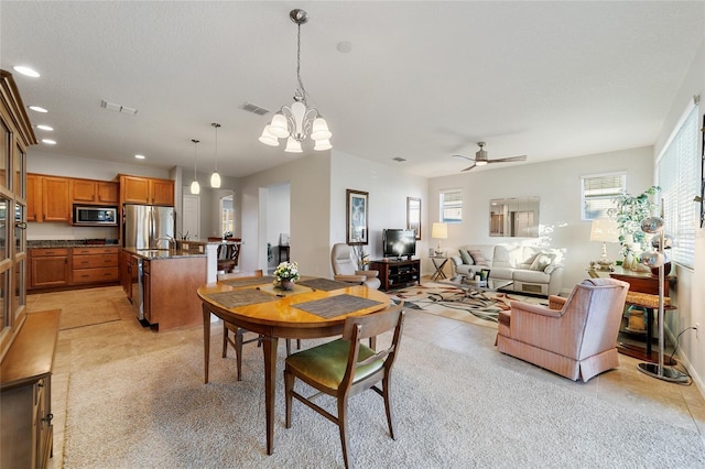 tiled dining space featuring ceiling fan with notable chandelier and a textured ceiling