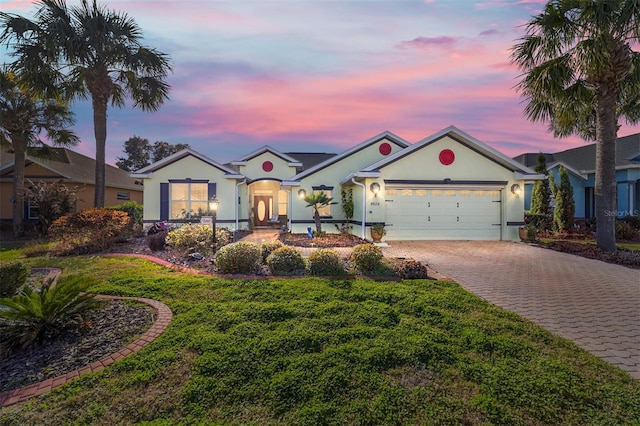 ranch-style house featuring a garage and a lawn