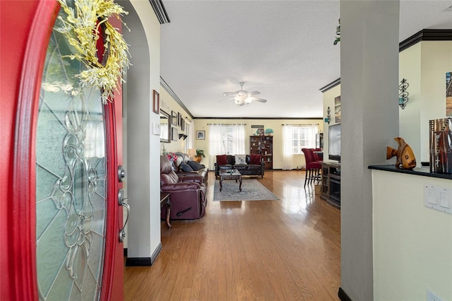 foyer entrance with wood-type flooring, a textured ceiling, ceiling fan, and crown molding