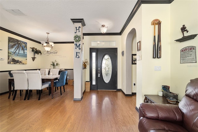 entrance foyer featuring wood-type flooring, ornamental molding, and a textured ceiling