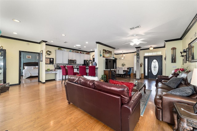 living room featuring crown molding, ceiling fan, and light wood-type flooring