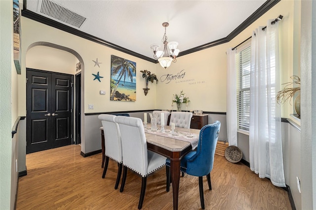 dining room with ornamental molding, a chandelier, and hardwood / wood-style floors