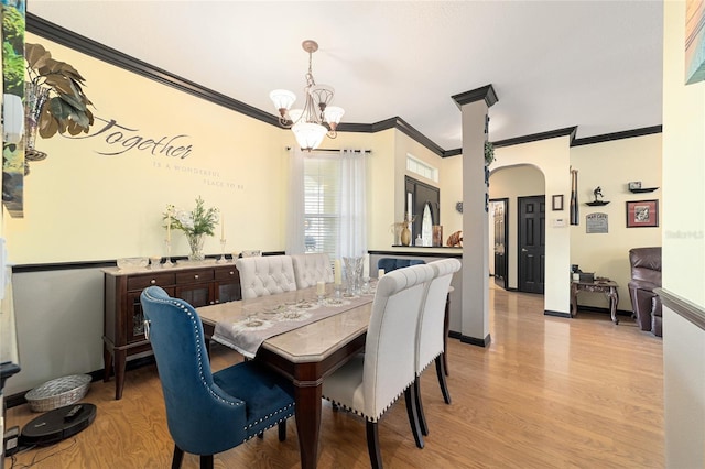 dining space with ornamental molding, an inviting chandelier, and light hardwood / wood-style flooring