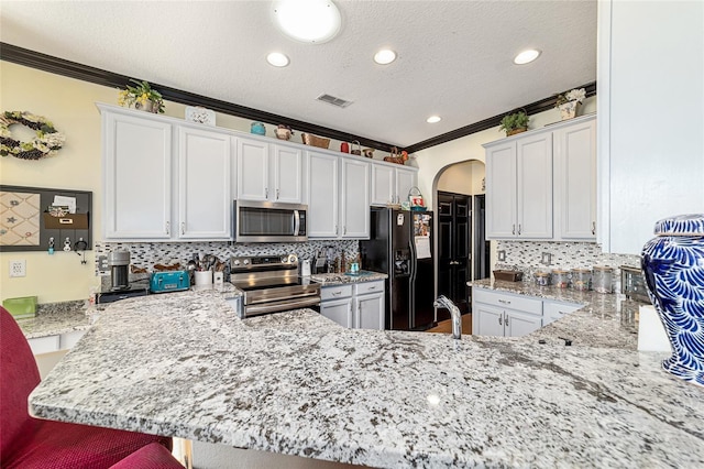 kitchen with appliances with stainless steel finishes, kitchen peninsula, a breakfast bar area, and white cabinets