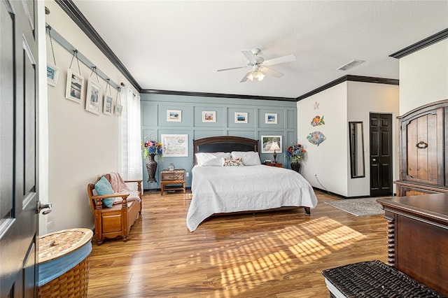 bedroom featuring ceiling fan, crown molding, a textured ceiling, and hardwood / wood-style flooring