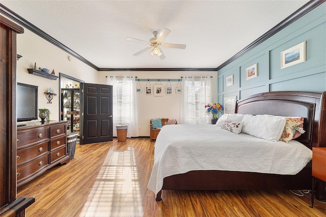 bedroom featuring ceiling fan, crown molding, light hardwood / wood-style floors, and a textured ceiling